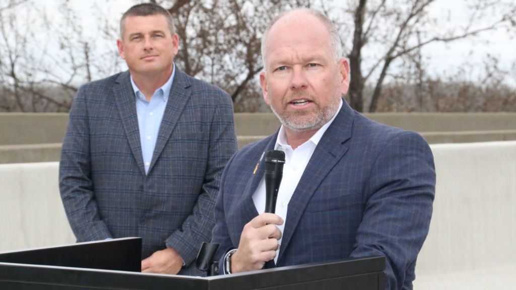 INDOT Commissioner Michael Smith speaking at the State Road 249 opening as emcee and Burns Harbor Port Director Ryan McCoy listens