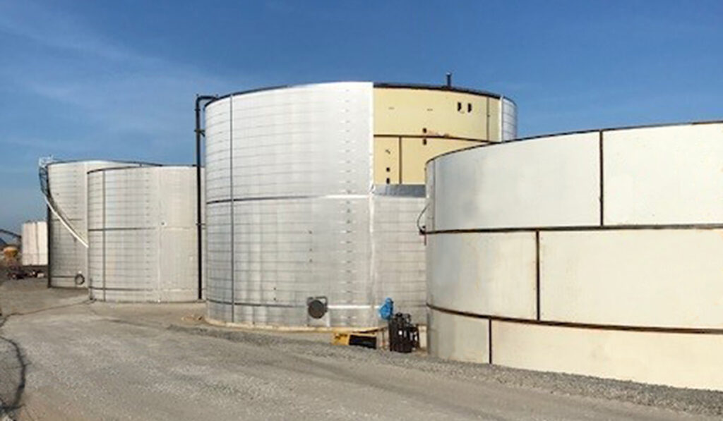 The contrast of a completed steel tank without the insulating wrap (right) with wrapping nearly complete (left)